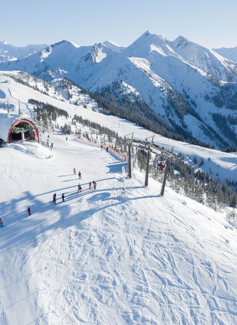 Luftaufnahme zeigt Skipiste mit Sessellift und Skifahrern vor verschneiter Alpenlandschaft. | © Dorfgasteiner Bergbahnen AG