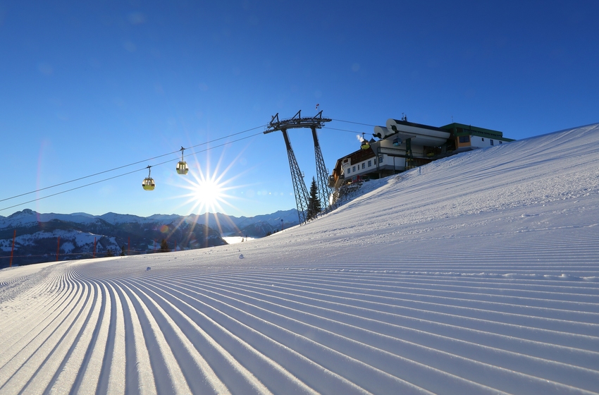 Gondola ascends at sunrise over freshly groomed slope toward the mountain station in a snowy ski area. | © Tourismusverband Großarltal
